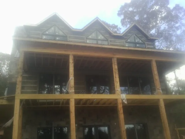Dormers and porch framing on a large log home under construction — Roof Coating work by our crew in Big Rock