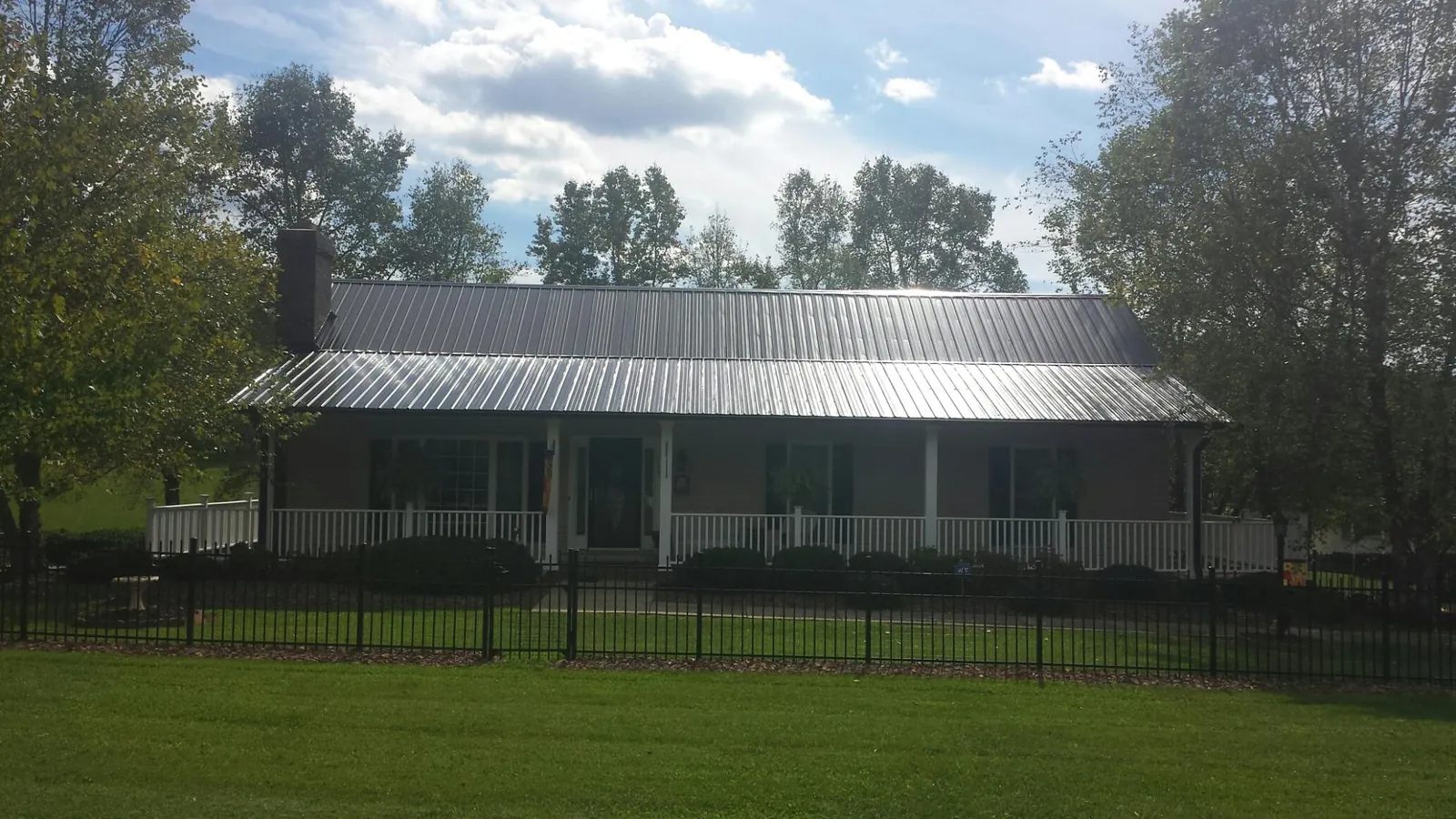 Gray metal roof on a brick ranch with a full width front porch — Gutter Guard Installation work by our crew in Big Rock